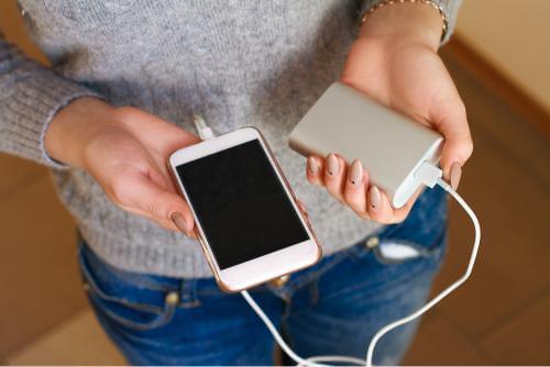 Person holding a phone and a portable charger